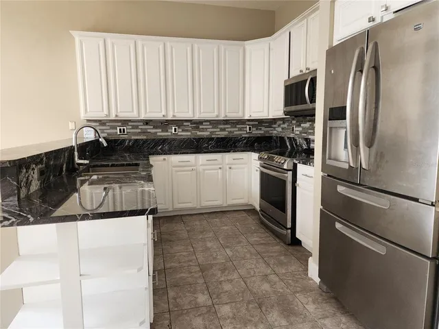 a kitchen with stainless steel appliances granite countertop a stove a sink and a refrigerator