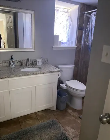 a bathroom with a granite countertop toilet sink and mirror