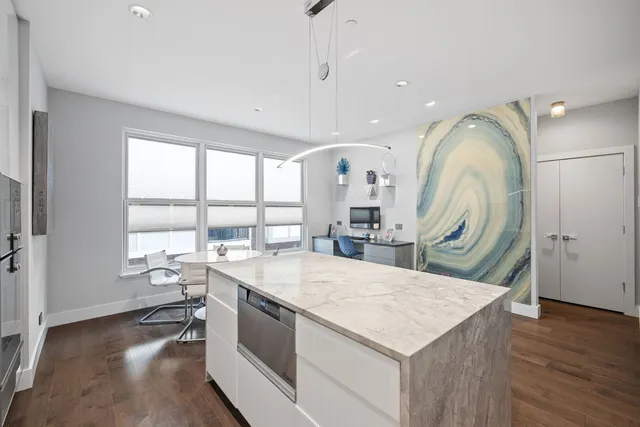 a living room with stainless steel appliances kitchen island a large window and wooden floor