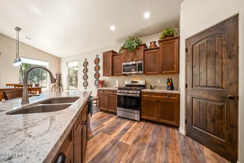 a kitchen with stainless steel appliances granite countertop a refrigerator a stove and a sink with wooden floors