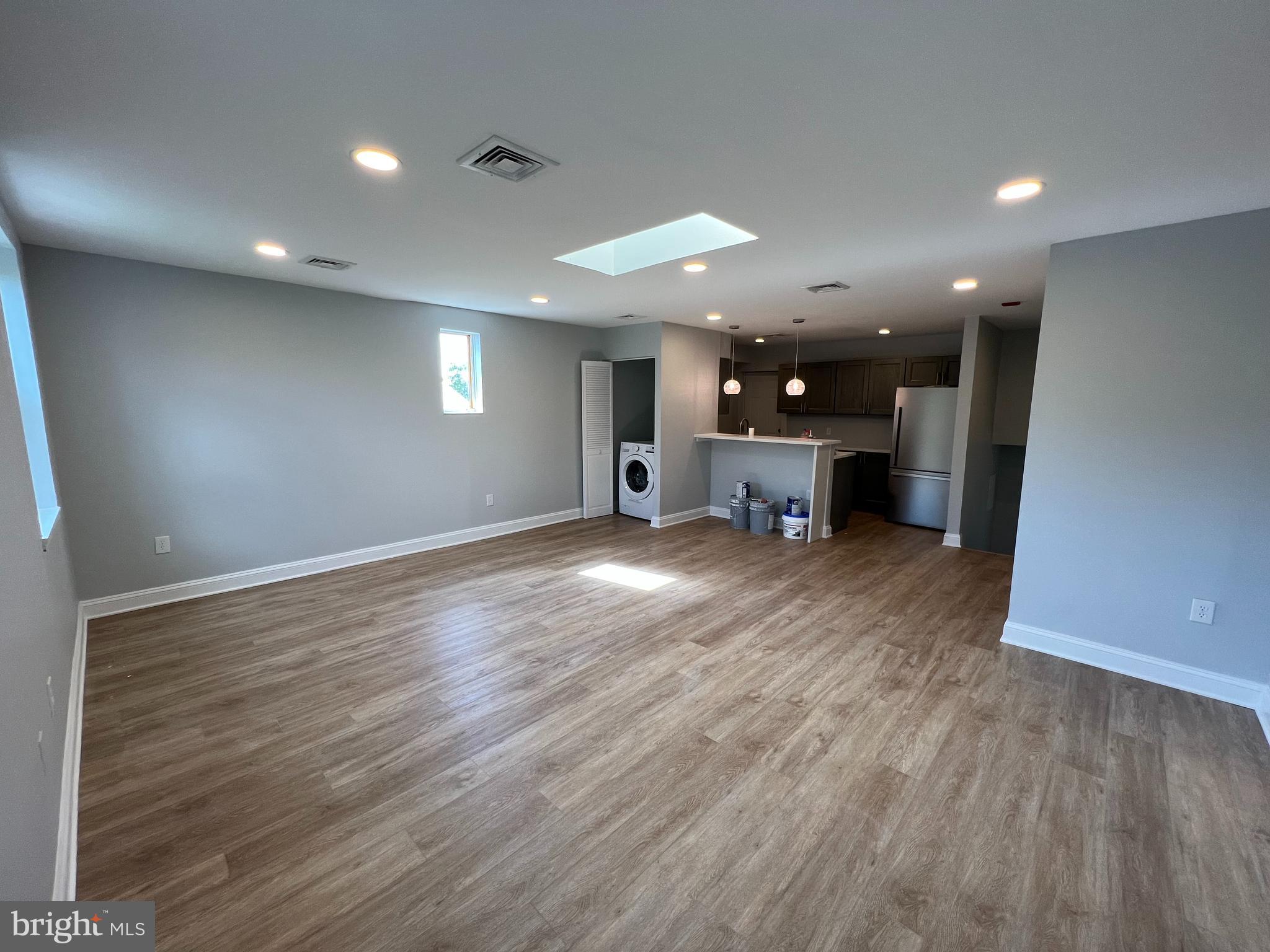 a view of a big room with wooden floor and a kitchen