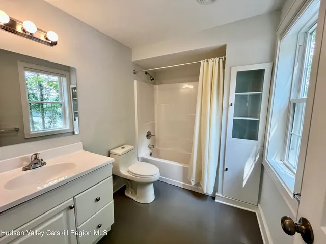 a bathroom with a double vanity sink toilet mirror and window