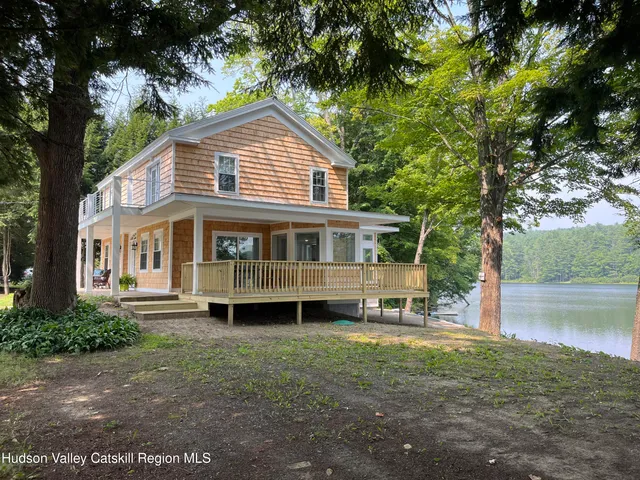 a front view of a house with a yard and a large tree