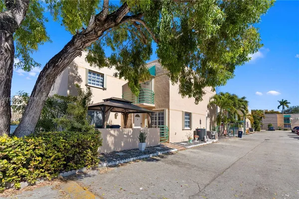 a view of a white house with a large tree