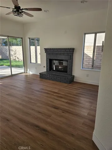 an empty room with wooden floor fireplace and windows