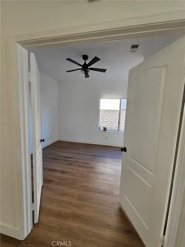 a view of a hallway with wooden floor and a ceiling fan