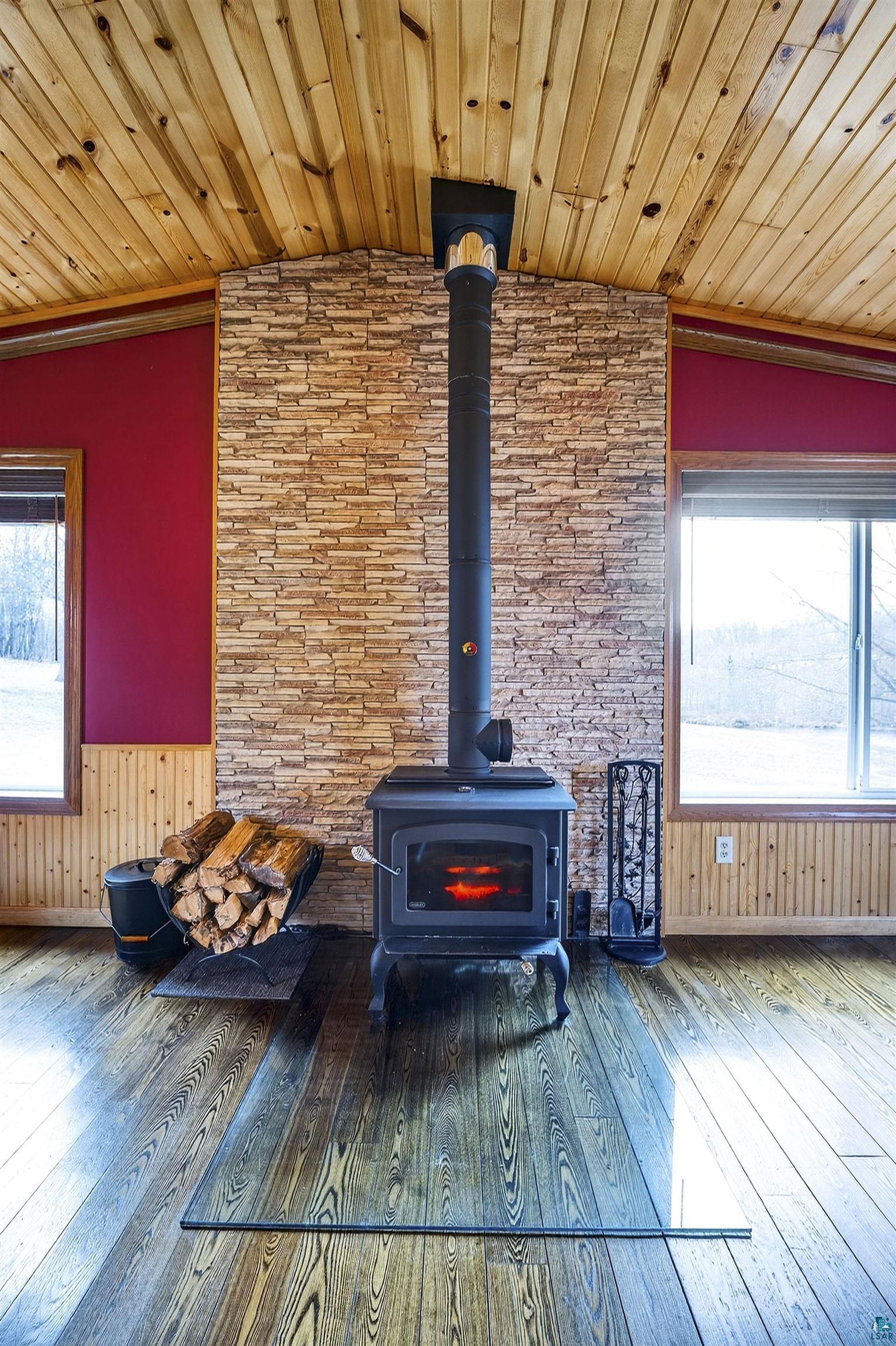 11702 East Mail Road Gordon, WI 54838 - Photo 27 of 43 Detailed view of wooden ceiling, ornamental molding, wood walls, wood finished floors, and a wood stove