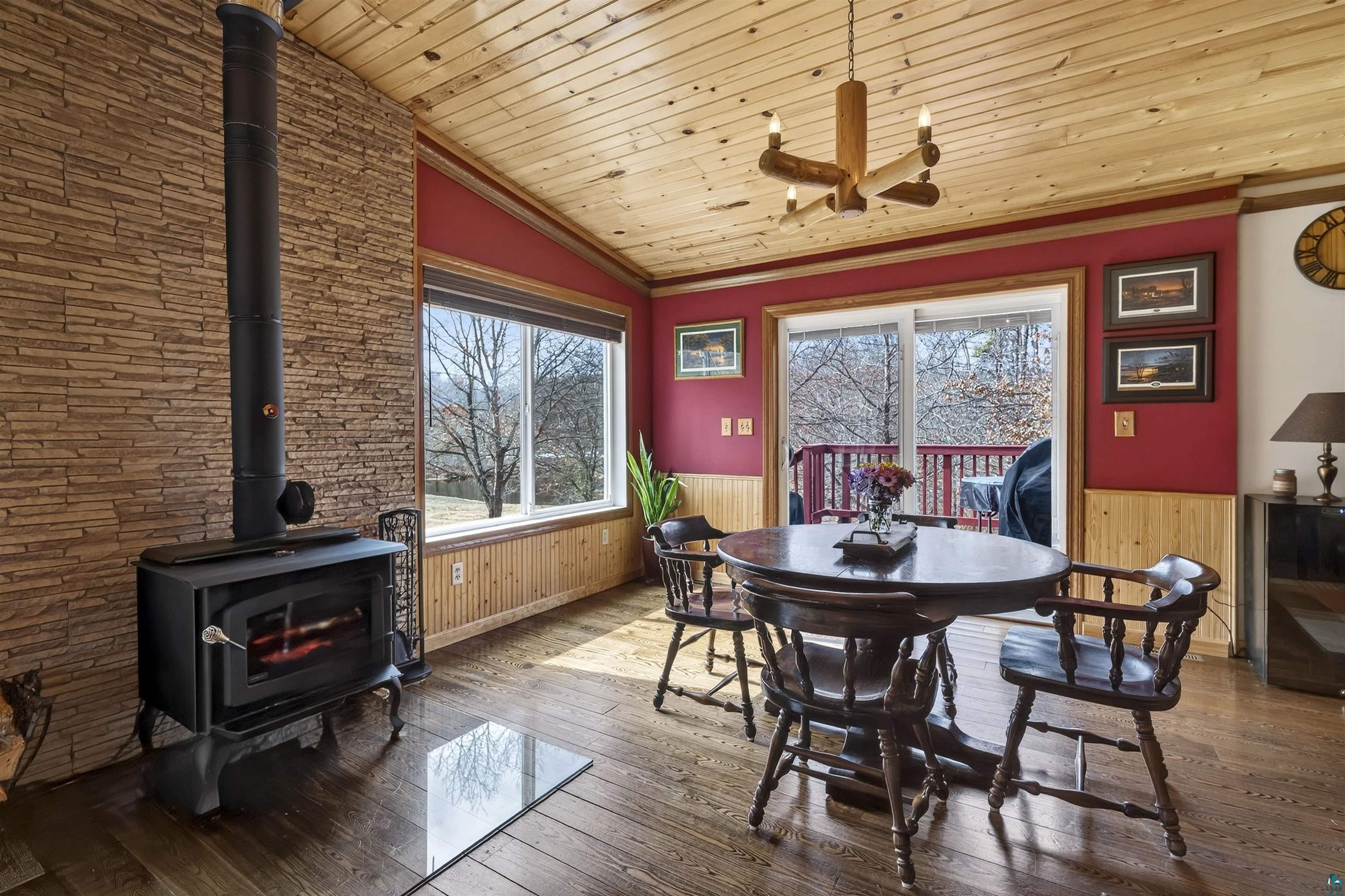 11702 East Mail Road Gordon, WI 54838 - Photo 28 of 43 Dining area featuring wainscoting, wood-type flooring, a wood stove, a vaulted wood ceiling, and wood walls