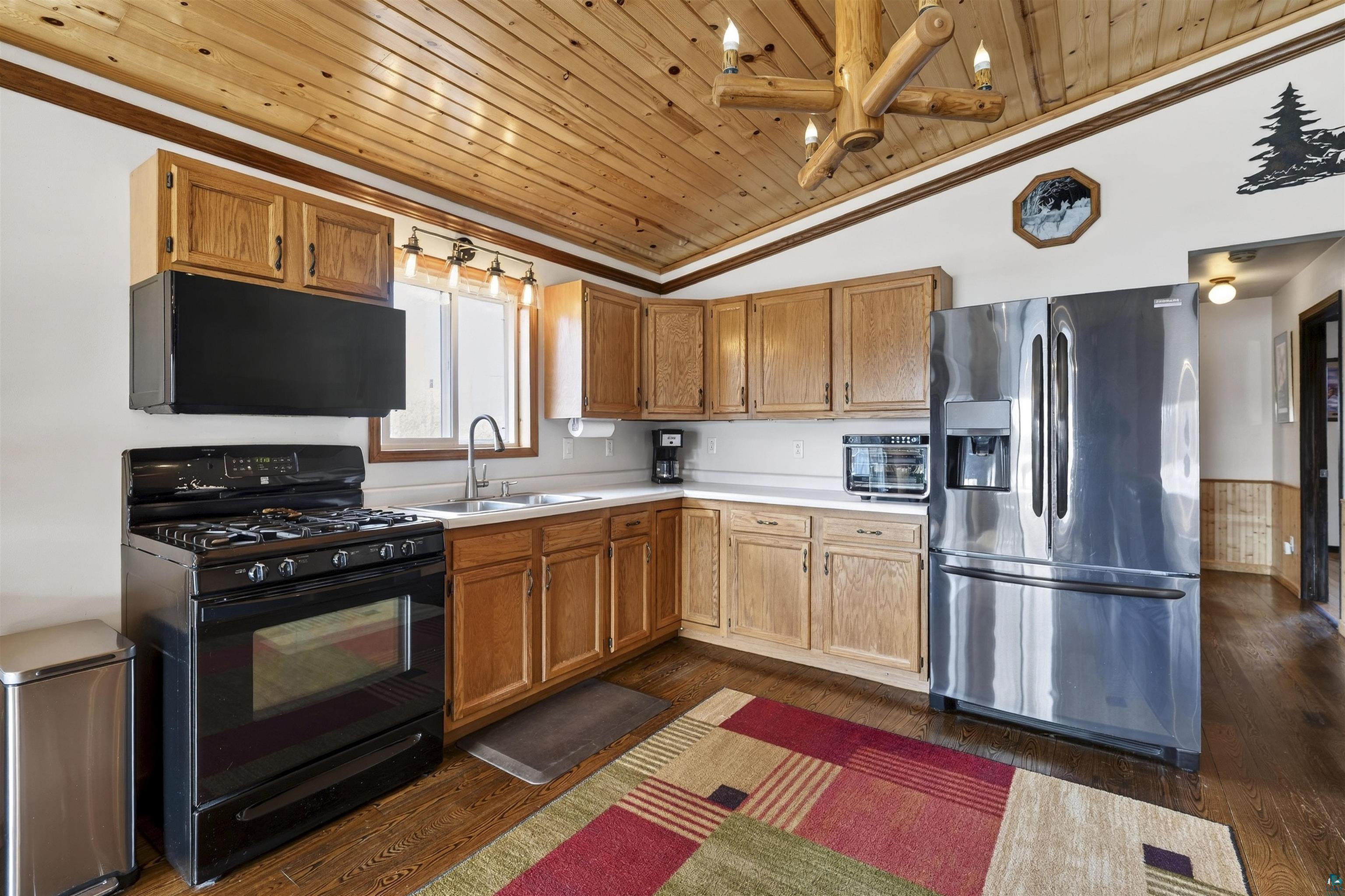 11702 East Mail Road Gordon, WI 54838 - Photo 30 of 43 Kitchen featuring black gas range, stainless steel fridge with ice dispenser, light countertops, dark wood-style flooring, and wood finish cabinetry