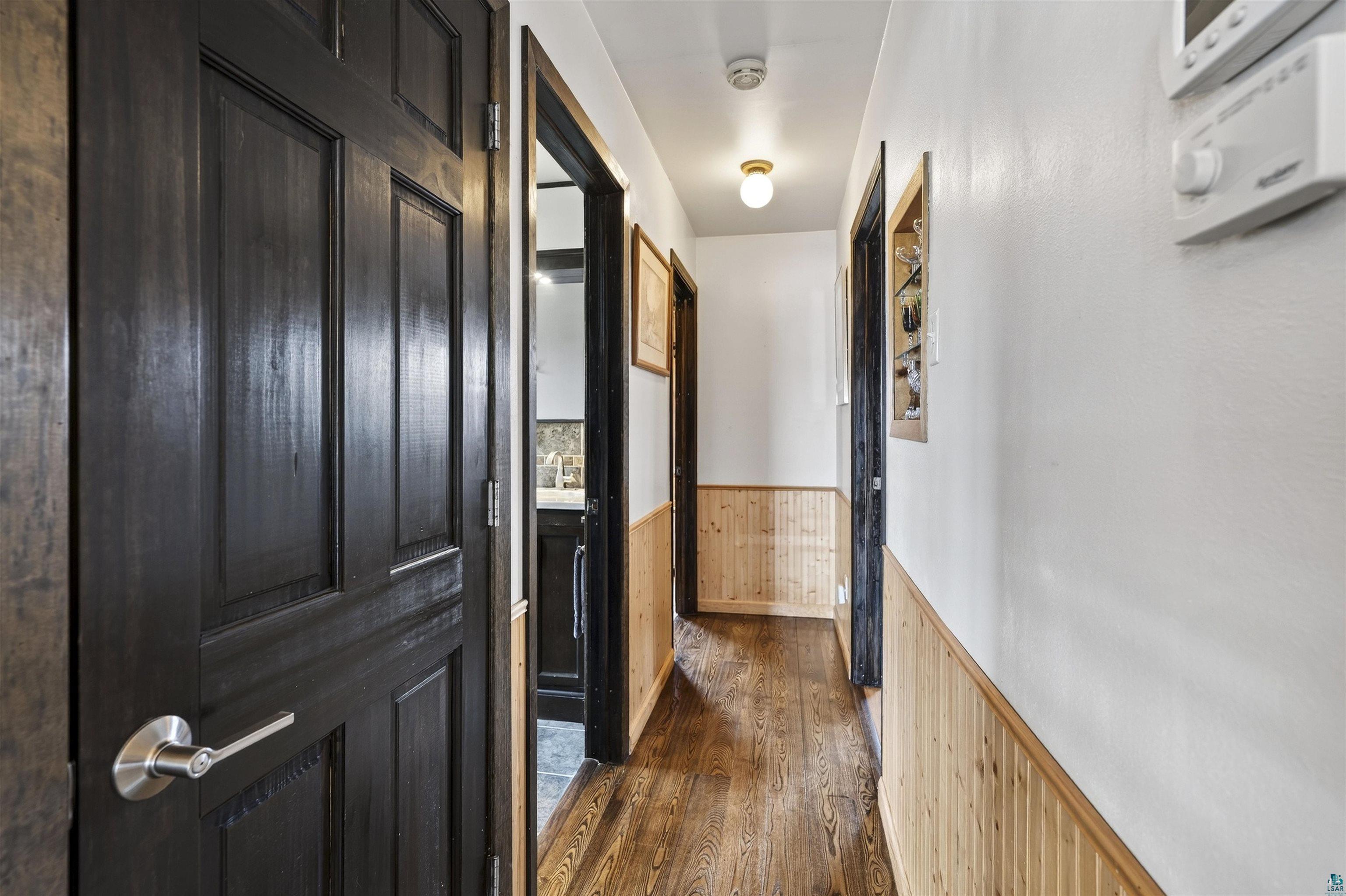 11702 East Mail Road Gordon, WI 54838 - Photo 34 of 43 Hall featuring a wainscoted wall, wooden walls, and dark wood-style floors