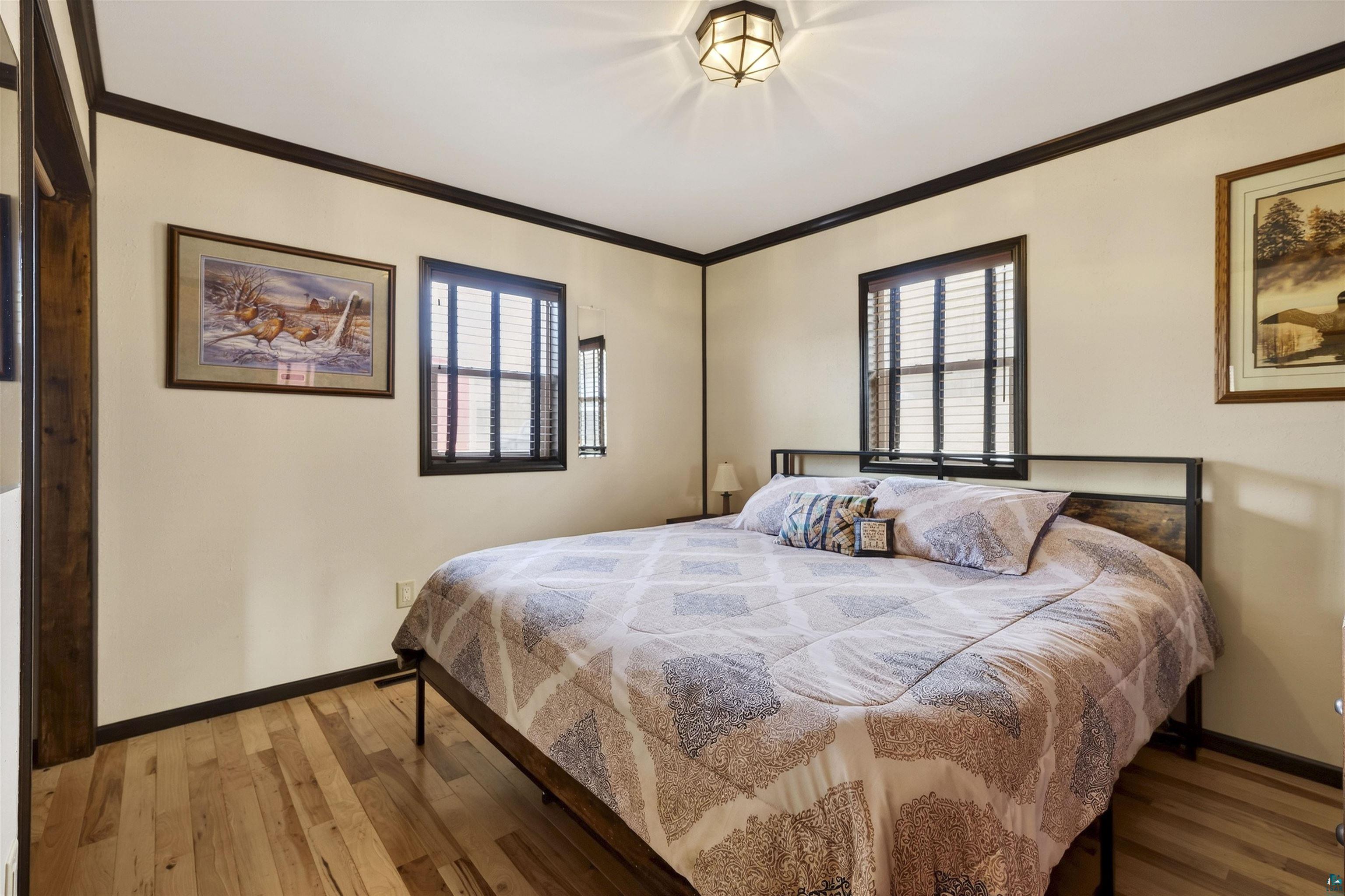 11702 East Mail Road Gordon, WI 54838 - Photo 40 of 43 Bedroom featuring hardwood / wood-style flooring, crown molding, and multiple windows