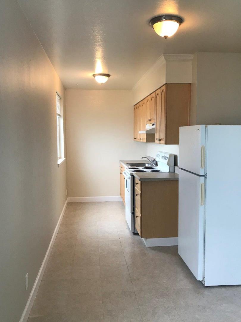445 Esplanade Avenue, Unit 2 Pacifica, CA 94044 - Photo 5 of 10 a kitchen with refrigerator a stove a microwave and white cabinets