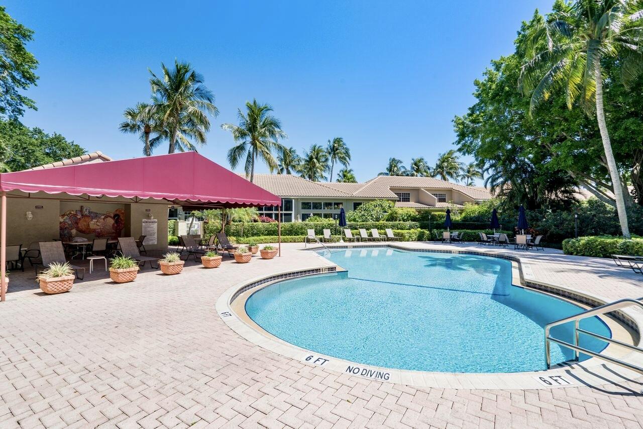 17270 Boca Club Boulevard, Unit 1707 Boca Raton, FL 33487 - Photo 53 of 68 a view of a swimming pool with lawn chairs under an umbrella