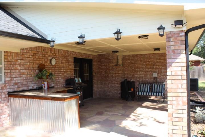 2020 Arbor Bend Road Bonham, TX 75418 - Photo 15 of 19 Covered patio featuring brick exterior walls, an outdoor kitchen with countertop space, a corrugated metal bar, and multiple affixed ceiling lights