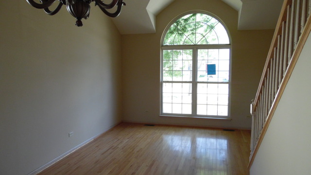 152 Sedgewicke Drive Romeoville, IL 60446 - Photo 2 of 16 an empty room with wooden floor fan and windows