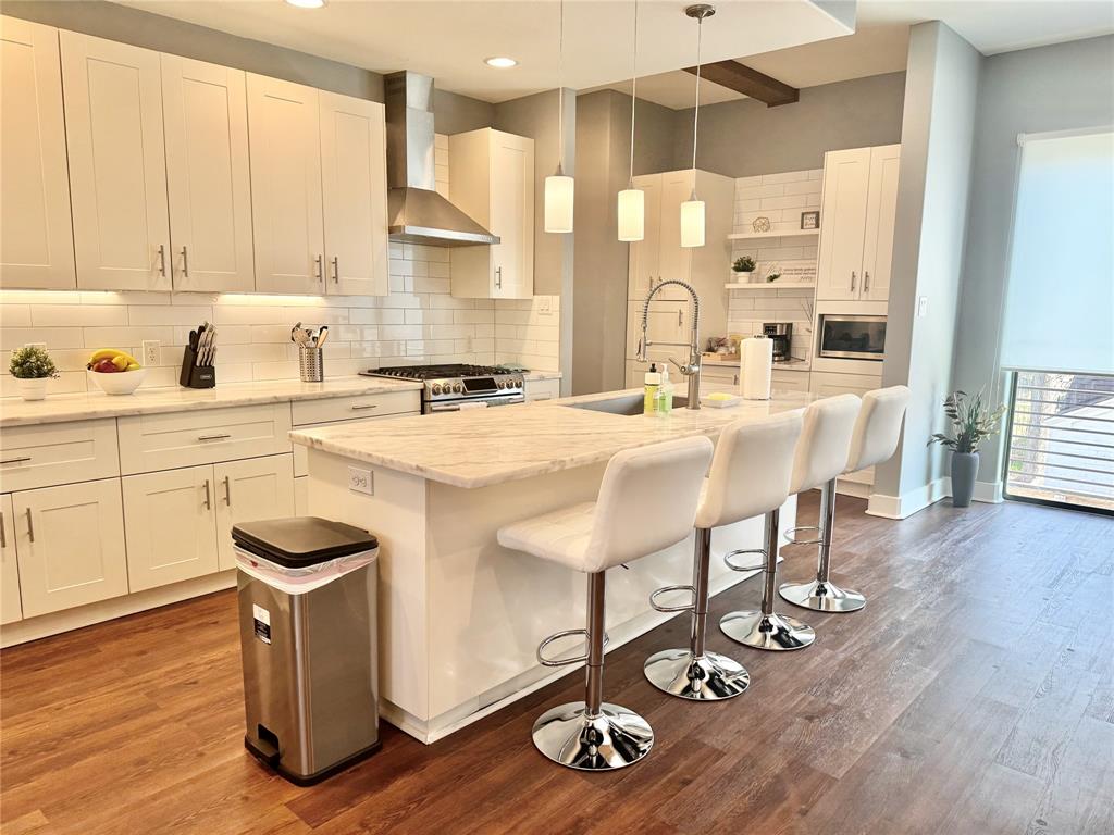 a kitchen with stainless steel appliances granite countertop a stove refrigerator and white cabinets with wooden floor