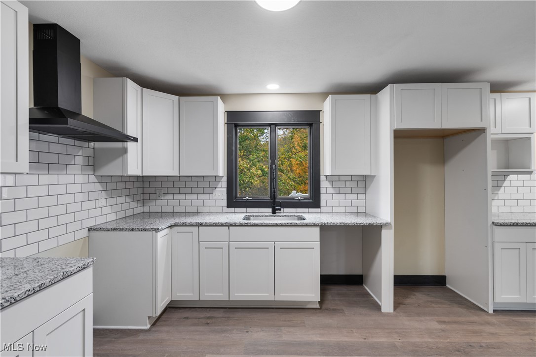 2201 Ridgewood Road Medina, OH 44256 - Photo 14 of 50 Kitchen featuring wall chimney exhaust hood, white cabinets, light wood-type flooring, decorative backsplash, and recessed lighting