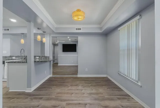 a view of a hallway to a room with wooden floor and cabinet