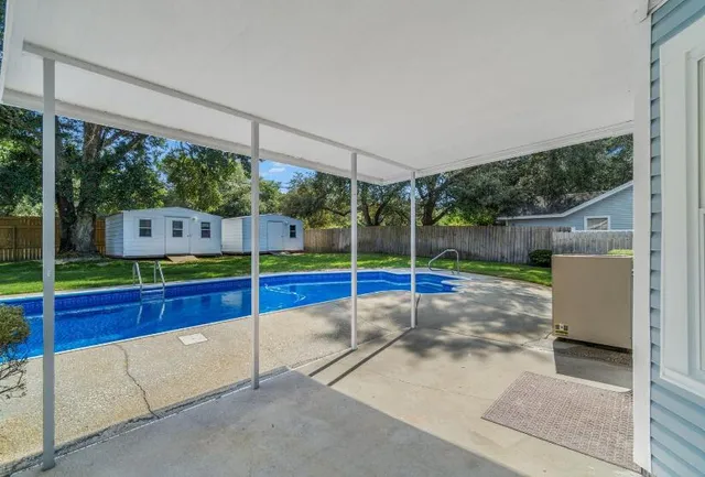 a view of house with yard outdoor seating and covered with trees in the background