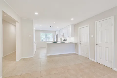 a large white kitchen with a refrigerator a sink and white cabinets