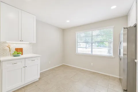 a kitchen with white cabinets and window