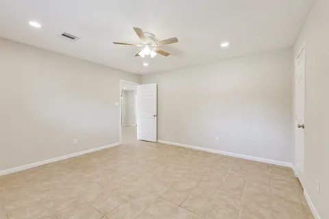 an empty room with a ceiling fan and a window