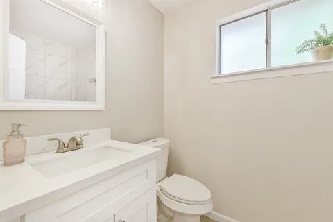 a bathroom with a sink vanity mirror and toilet