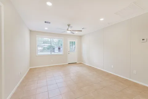 an empty room with windows and ceiling fan