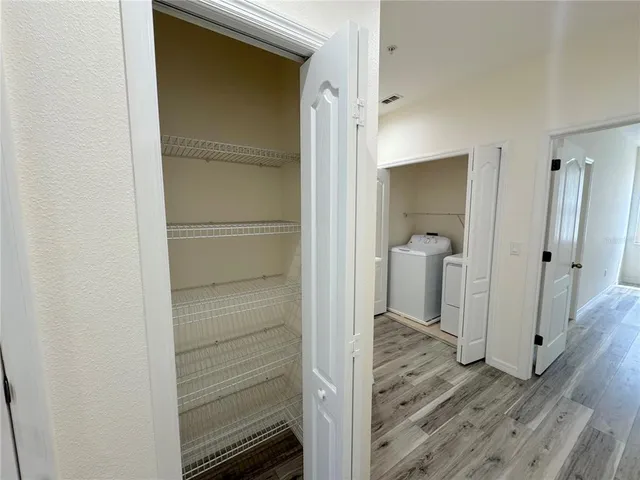 a view of a hallway with wooden floor and a cabinet