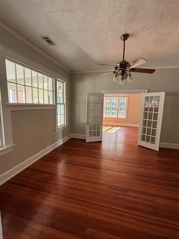 a view of an empty room with wooden floor and a window