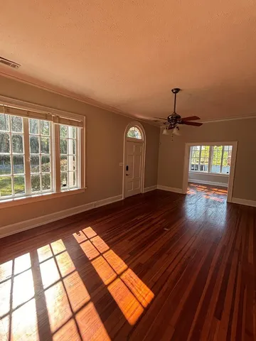 a view of empty room with wooden floor and fan