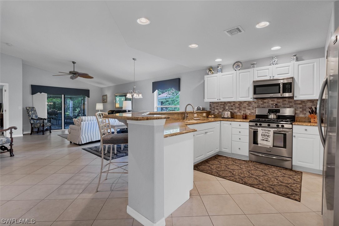 19654 Villa Rosa Loop Estero, FL 33967 - Photo 5 of 37 a kitchen with stainless steel appliances granite countertop a refrigerator oven a sink a dining table and chairs