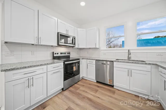 a kitchen with stainless steel appliances granite countertop a stove a sink and a microwave