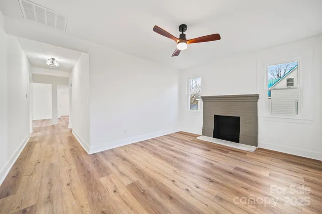 a view of empty room with wooden floor and fireplace