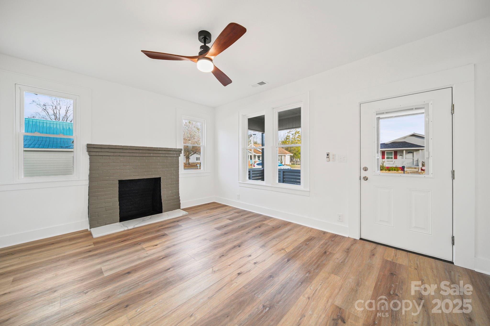 1703 Lowder Street Albemarle, NC 28001 - Photo 10 of 31 wooden floor in an empty room with a fireplace