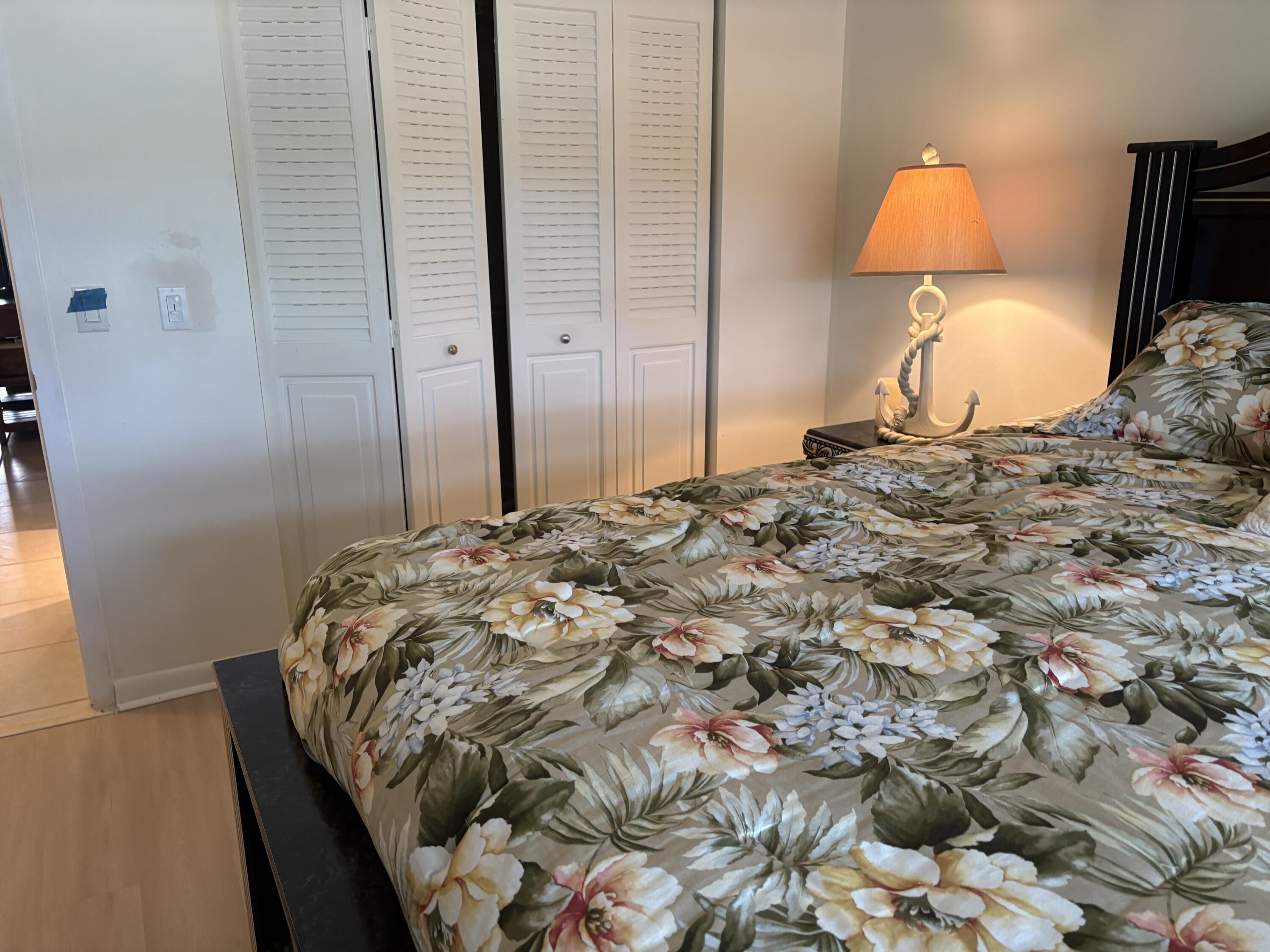 124 Dorset C, Unit 124C Boca Raton, FL 33434 - Photo 14 of 21 a bedroom with a bed and a lamp
