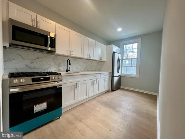 a kitchen with stainless steel appliances granite countertop a sink a stove a microwave and wooden cabinets