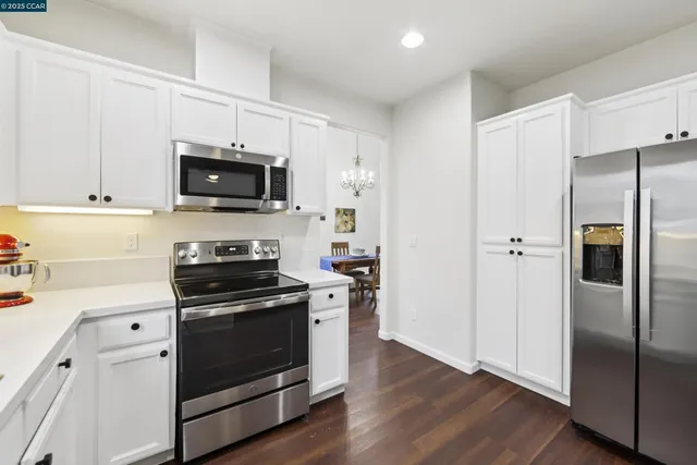 a kitchen with cabinets stainless steel appliances and wooden floor