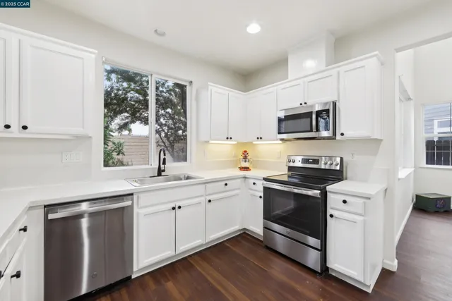 a kitchen with stainless steel appliances a sink cabinets and a window