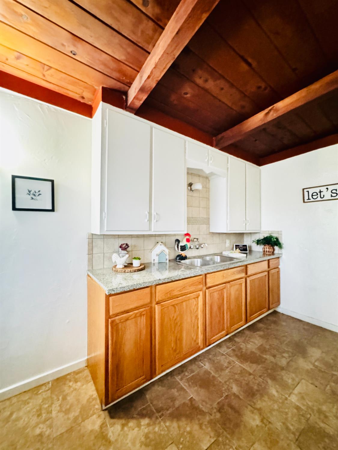 1630 Paradise Road Modesto, CA 95358 - Photo 14 of 42 kitchen featuring a wood ceiling with exposed beams, decorative backsplash, dual tone cabinets, and light stone countertops