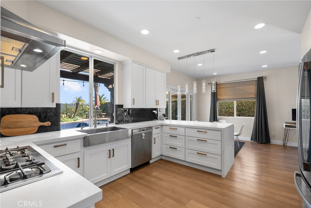 25742 Lewis Way Stevenson Ranch, CA 91381 - Photo 25 of 66 a kitchen with stainless steel appliances a stove a sink dishwasher and white cabinets with wooden floor