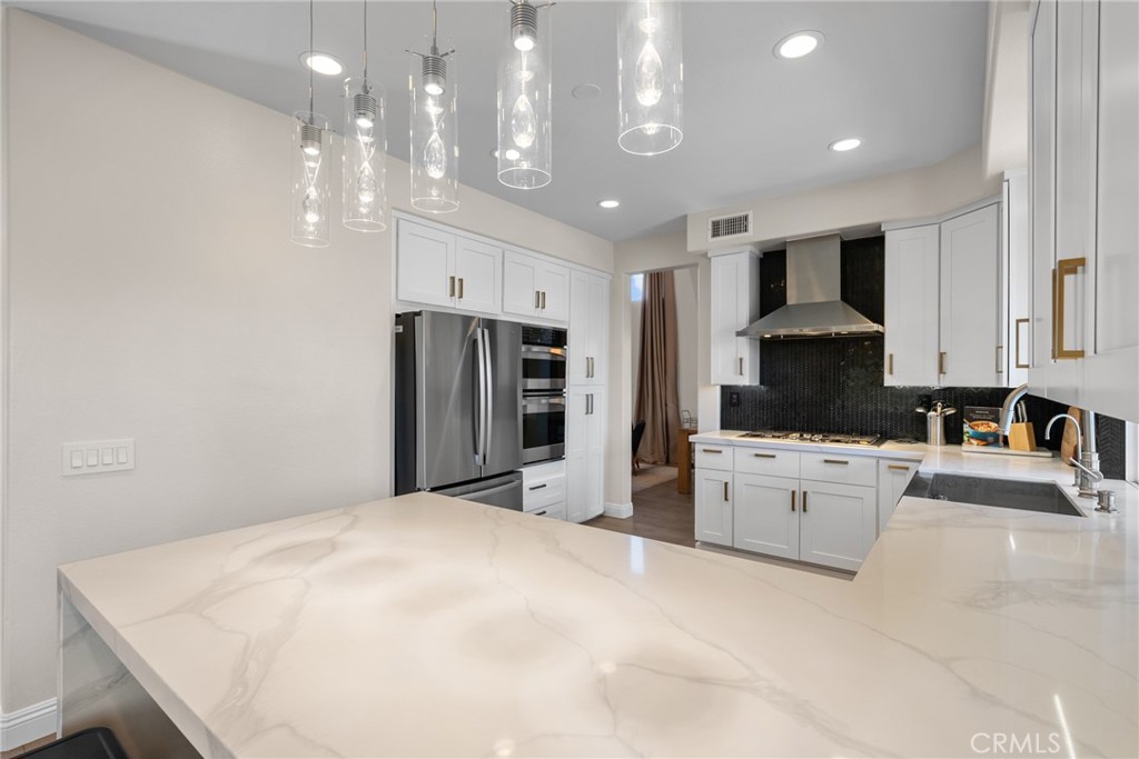 25742 Lewis Way Stevenson Ranch, CA 91381 - Photo 26 of 66 a large white kitchen with kitchen island a sink stainless steel appliances and cabinets