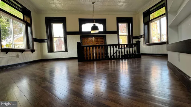 an empty room with wooden floor fireplace and windows