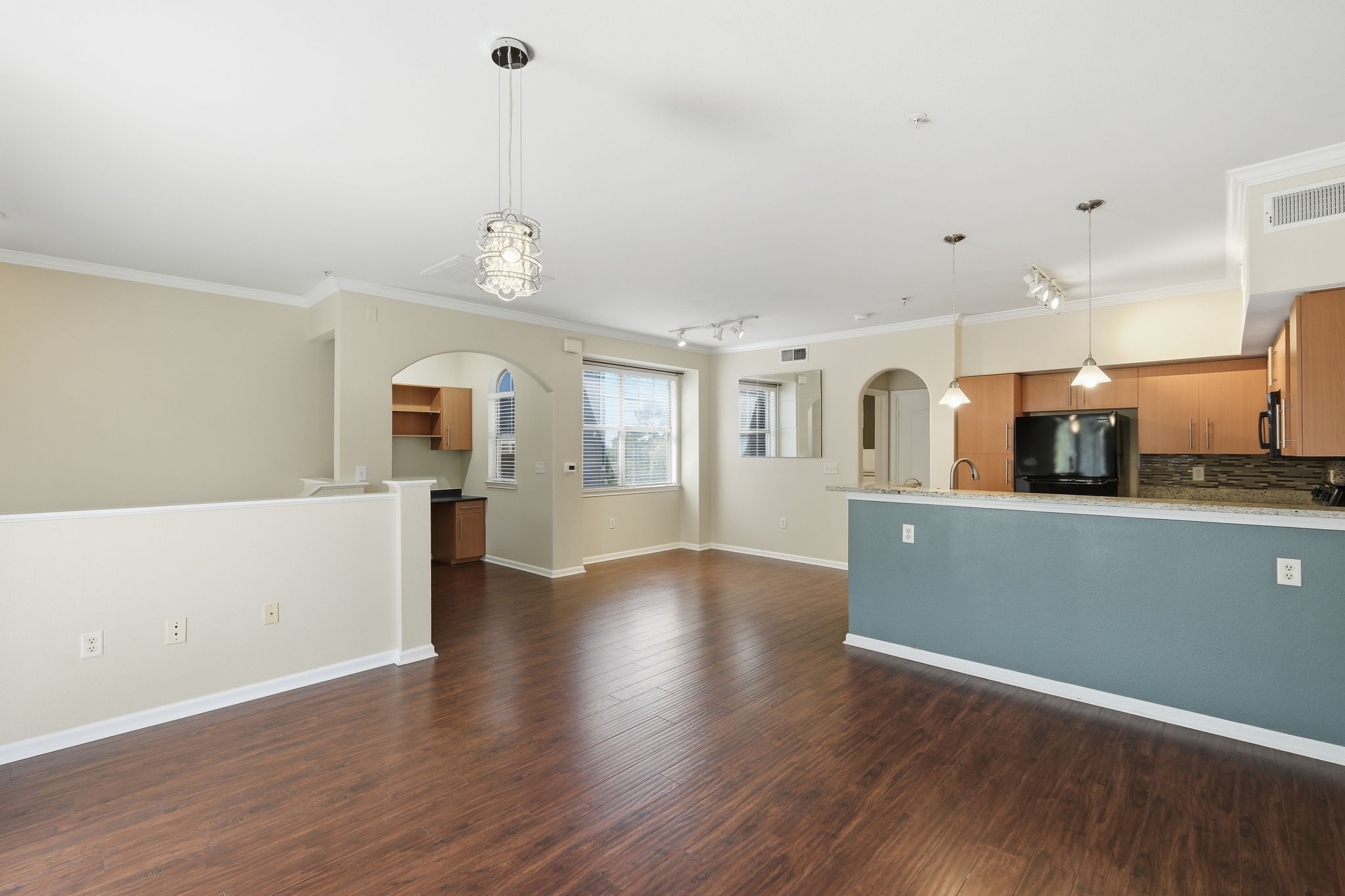 11203 Ranch Road 2222, Unit 2305 Austin, TX 78732 - Photo 4 of 19 Kitchen featuring crown molding, freestanding refrigerator, light stone counters, dark wood-style flooring, and arched walkways