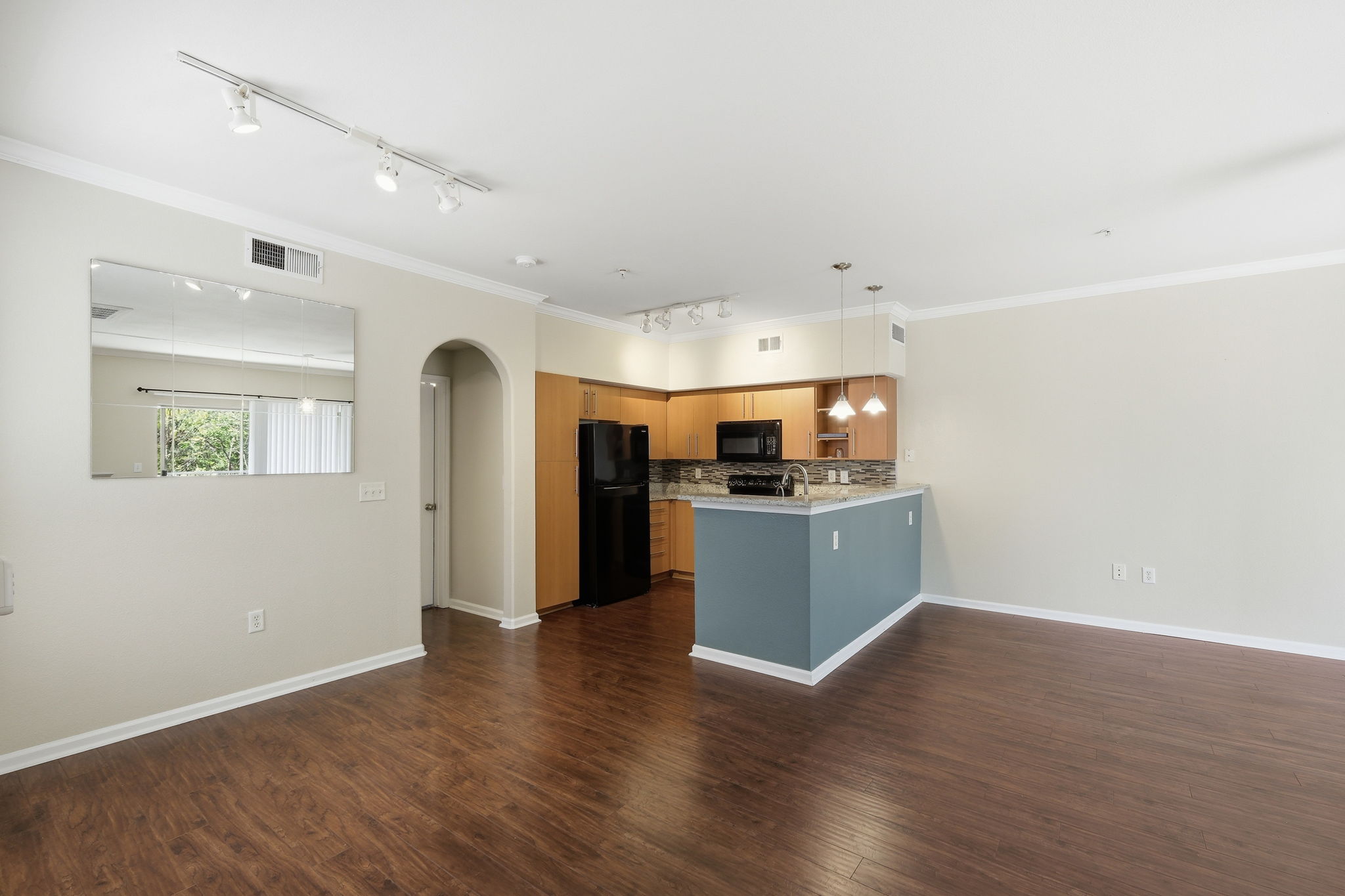 11203 Ranch Road 2222, Unit 2305 Austin, TX 78732 - Photo 6 of 19 Kitchen featuring arched walkways, black appliances, a peninsula, ornamental molding, and dark wood finished floors