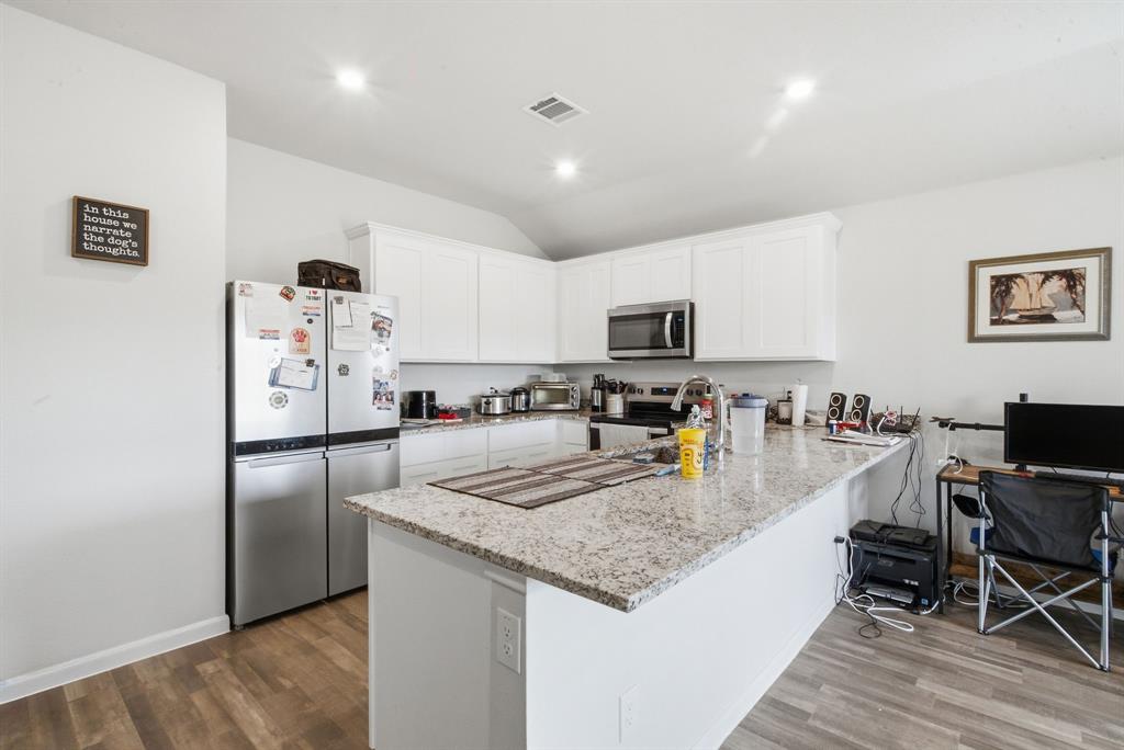 417 Jameson Springtown, TX 76082 - Photo 11 of 25 Kitchen featuring white cabinetry, stainless steel appliances, speckled stone countertops, and wood-finish flooring