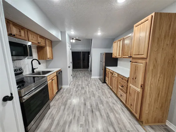 a kitchen with granite countertop a refrigerator oven a sink dishwasher and wooden cabinets with wooden floor