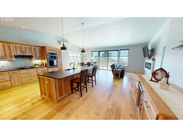 a living room with stainless steel appliances kitchen island granite countertop a table chairs and a refrigerator