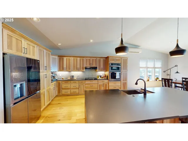 a kitchen with kitchen island stainless steel appliances a sink a counter top space cabinets and a view of living room