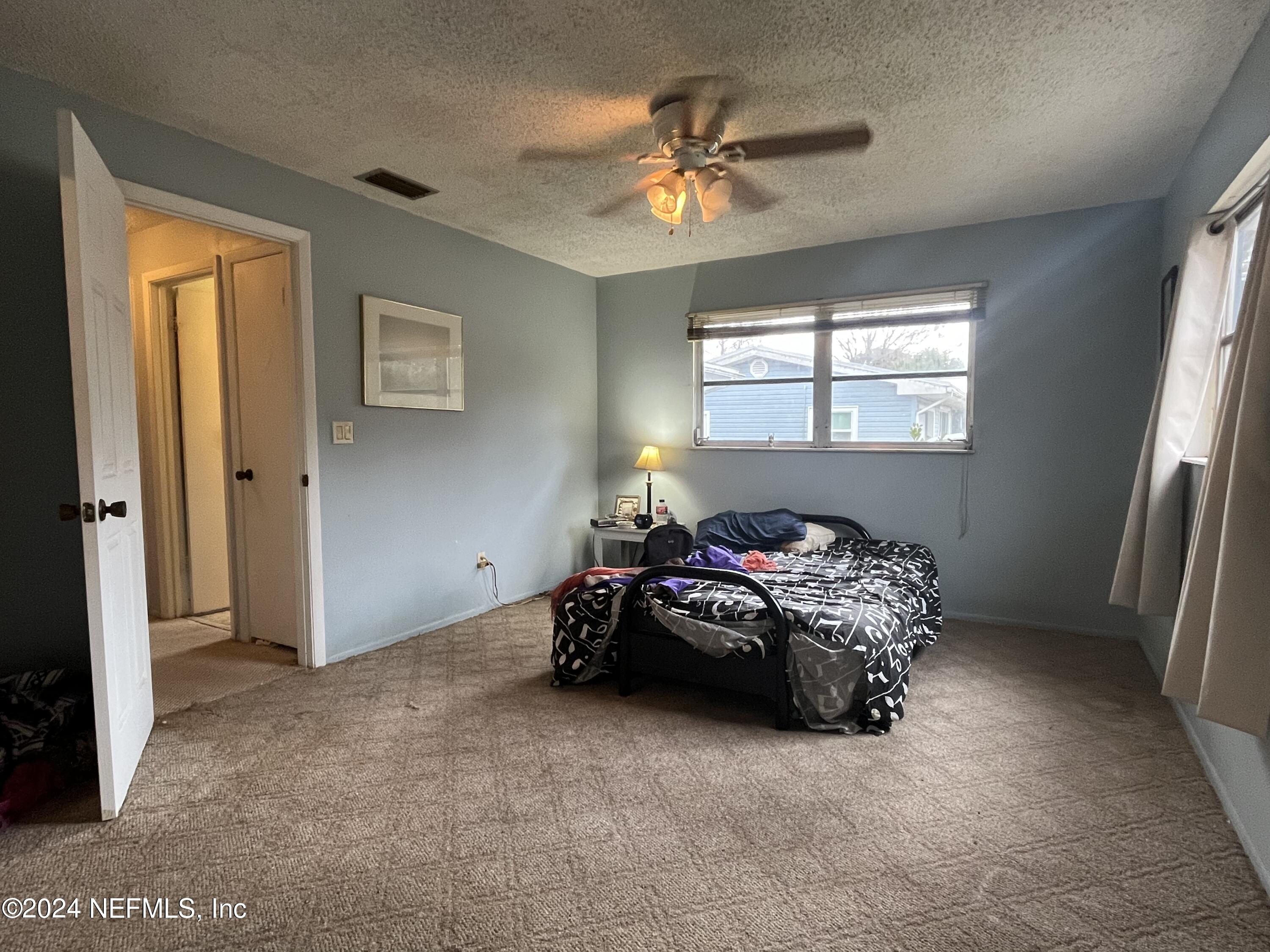 228 Lily Road St. Augustine, FL 32086 - Photo 22 of 34 a bedroom with a bed and a chandelier